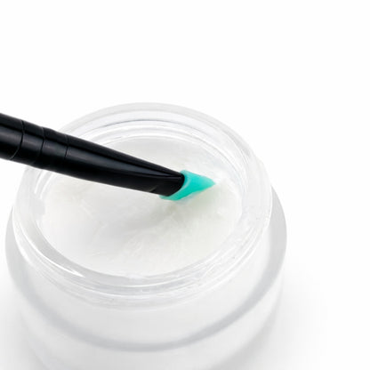 Jar of white lift &amp; lami balm with a black and green applicator on a white background